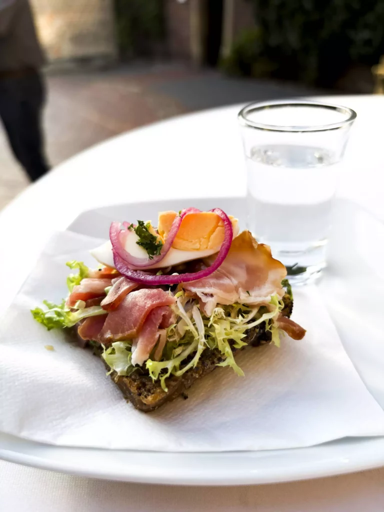 Belegtes Schwarzbrot mit Schinken, Ei, Salat und Zwiebelringen