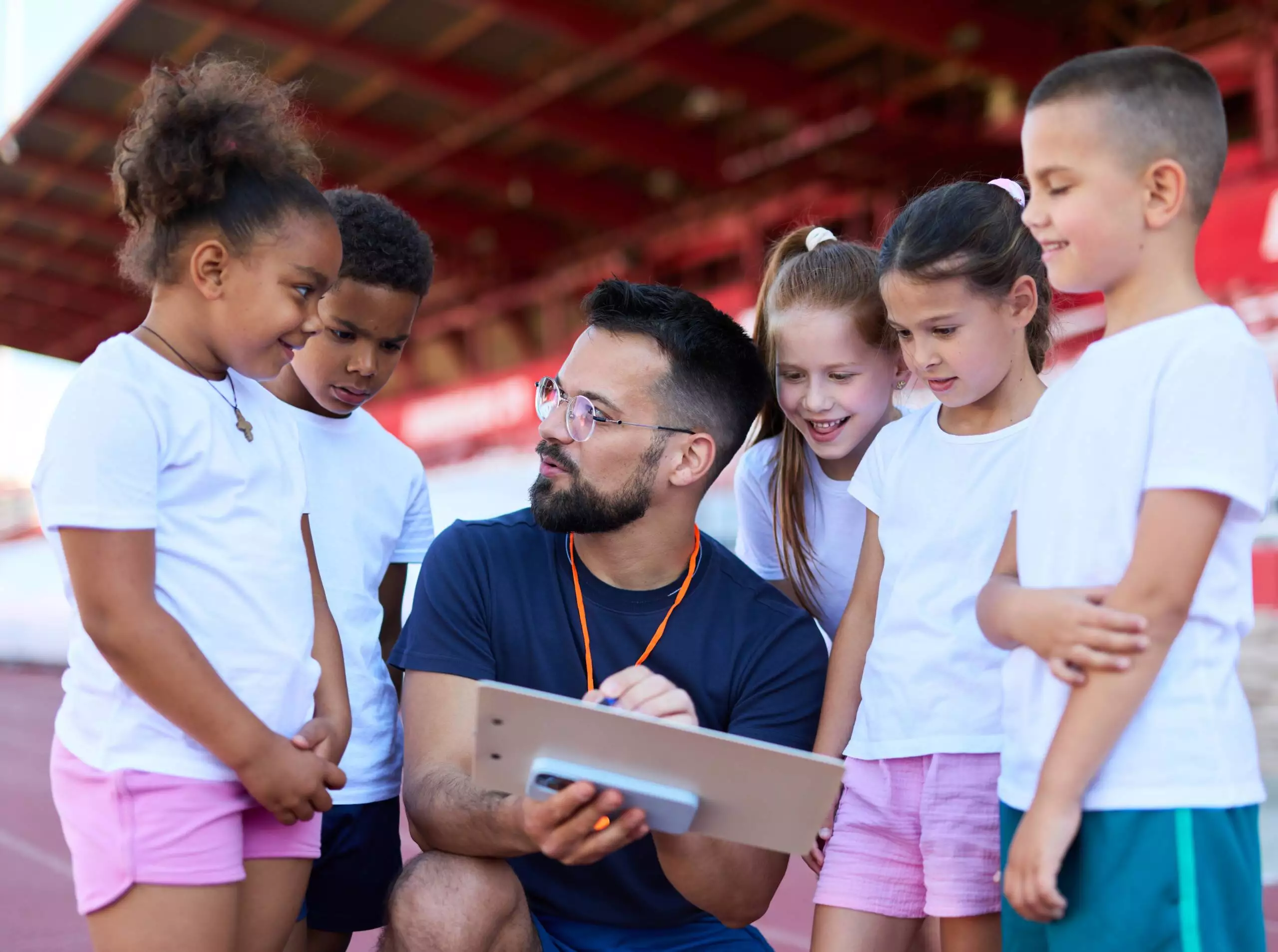 Trainer spricht mit Kindern auf dem Sportplatz